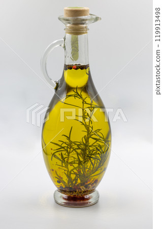 Transparent bottle of olive oil with herbs and seeds closeup. Transparent bottle of olive oil with herbs and seeds closeup. 119913498