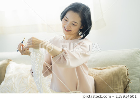 Middle-aged woman knitting in the living room 119914601
