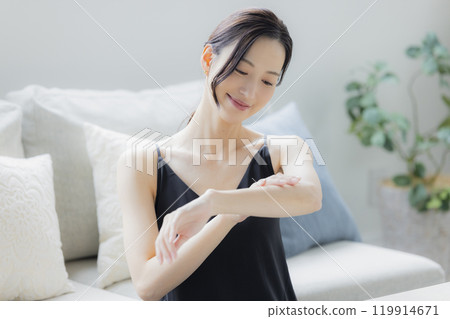 A woman doing skin care in the living room 119914671