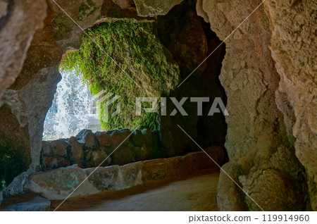 A path that goes behind a small waterfall in the park A path that goes behind a small waterfall in the park 119914960