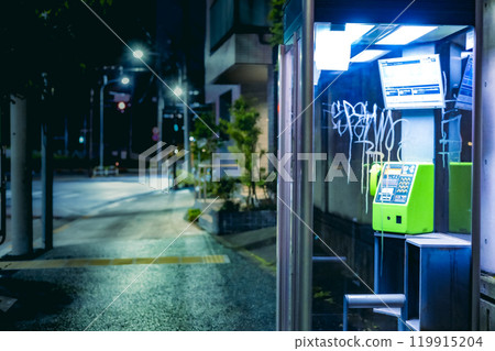 A graffitied public telephone booth at night 119915204