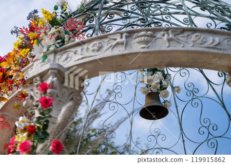White arch gate decorated with roses and bells 119915862