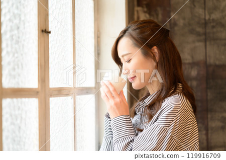 A woman drinking coffee at the window 119916709