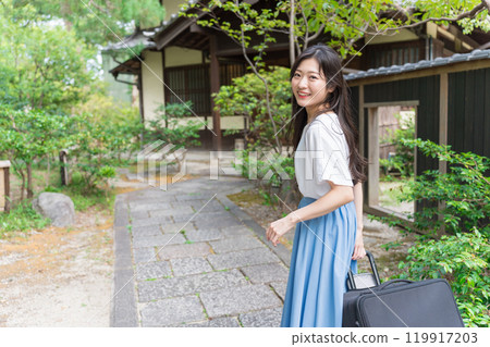 一位年輕女子背著行李箱返回鄉村的旅行形象 119917203