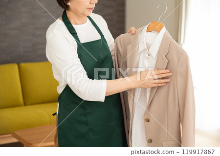 一位高級女主婦/管家在房子的客廳裡穿著綠色圍裙和西裝外套 119917867