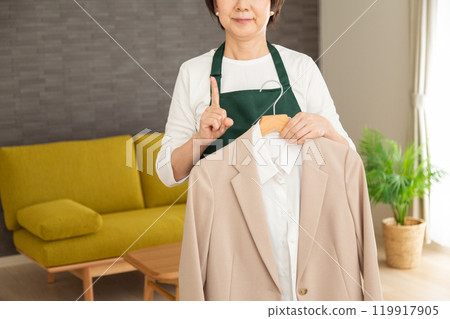 身穿綠色圍裙、拿著西裝外套、食指指向自家客廳的高級女主角/管家 119917905