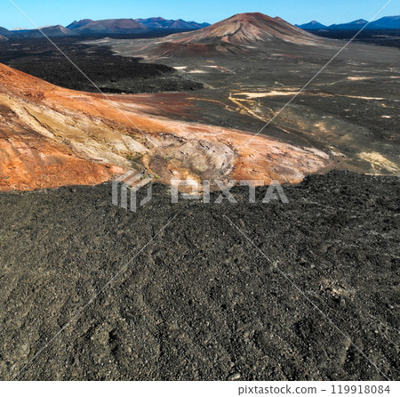 A red mountain, black volcanic ground and lava formations, volcanoes A red mountain, black volcanic ground and lava formations, volcanoes 119918084