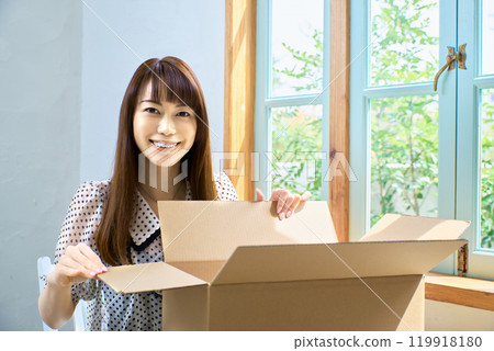 Woman opening a cardboard box 119918180