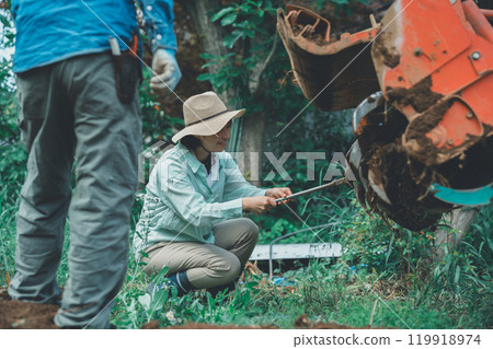 A farmer removing soil from a tractor rotary A farmer removing soil from a tractor rotary 119918974