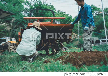 Farmer removing mud from tractor rotary 119918978