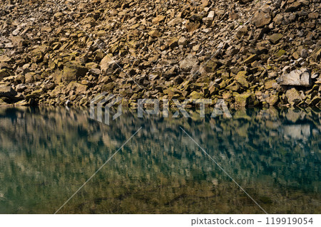 Rocky Shoreline Reflected in Clear Alpine Lake Rocky Shoreline Reflected in Clear Alpine Lake 119919054