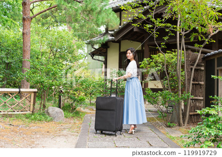 A young woman pulling a suitcase and returning to the countryside Travel image 119919729