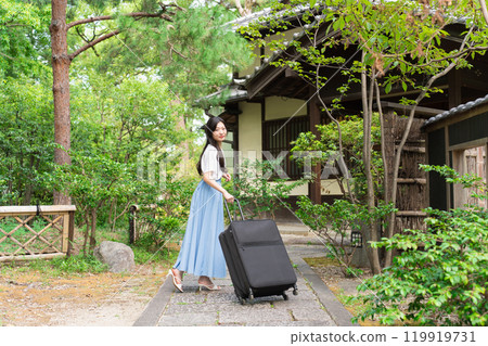 A young woman pulling a suitcase and returning to the countryside Travel image 119919731