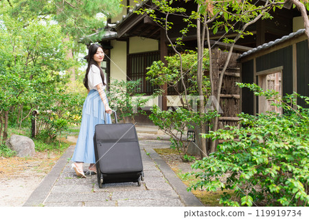 A young woman pulling a suitcase and returning to the countryside Travel image 119919734