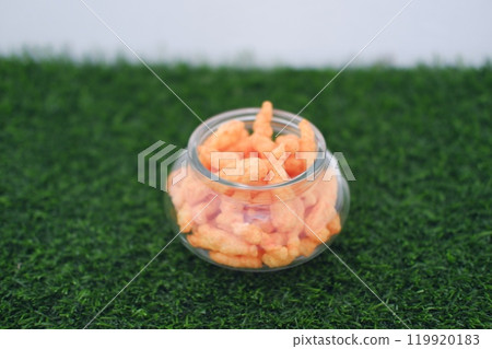 Crispy Corn Puffs in a jar on grass. Selective focus 119920183