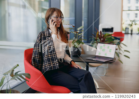 A Professional Woman is Engaged in Work Remotely Within a Modern and Stylish Office Space 119920243