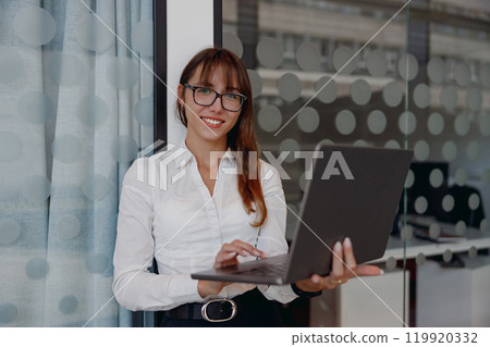 A Confident Businesswoman Working Diligently on Her Laptop in a Contemporary Office Space A Confident Businesswoman Working Diligently on Her Laptop in a Contemporary Office Space 119920332