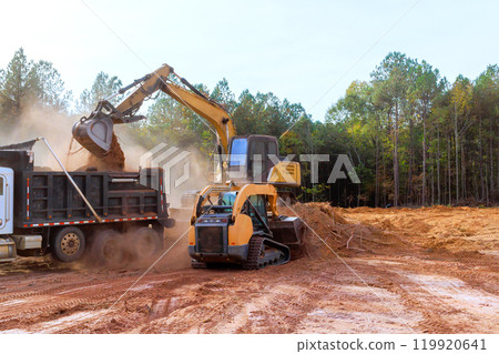 An excavator is used to load earth into dump truck on construction site. An excavator is used to load earth into dump truck on construction site. 119920641