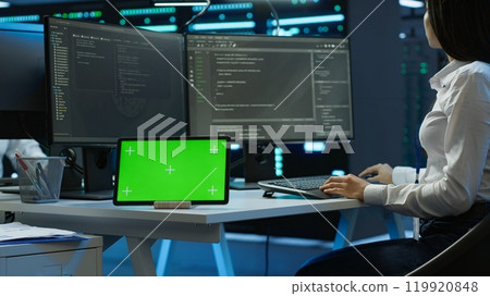 Data center developer responsible for installation of networking equipment solving tasks on green screen device. Woman doing maintenance on server room infrastructure using chroma key tablet, camera A 119920848