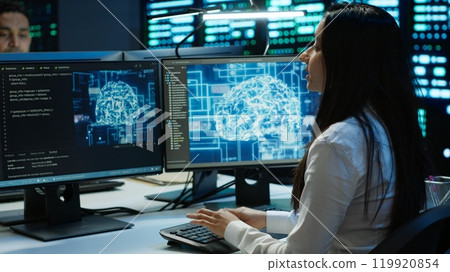 Technicians coworkers using AI tech on computer to do checkup in server room. Teamworking colleagues in data center using artificial intelligence technology to process datasets for training, camera A Technicians coworkers using AI tech on computer to do checkup in server room. Teamworking colleagues in data center using artificial intelligence technology to process datasets for training, camera A 119920854