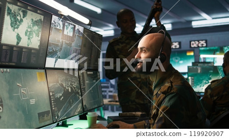 Army specialist working in war room operating surveillance tech, evaluating target data. Close up on dispatcher doing job in HQ base of operations, engaging enemy forces, camera B 119920907
