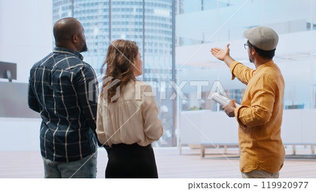 Corporate clients and a real estate agent negotiating a leasing contract, focusing on architectural blueprints, layout and investment potential of new office property. Hunting for deals. Camera A. Corporate clients and a real estate agent negotiating a leasing contract, focusing on architectural blueprints, layout and investment potential of new office property. Hunting for deals. Camera A. 119920977