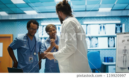 Cheerful confident doctors and nurses finding right treatment plan for a diagnosis, competent healthcare industry workers. Medical staff smiling and clapping hands, good news in a cabinet. Camera B. Cheerful confident doctors and nurses finding right treatment plan for a diagnosis, competent healthcare industry workers. Medical staff smiling and clapping hands, good news in a cabinet. Camera B. 119920997