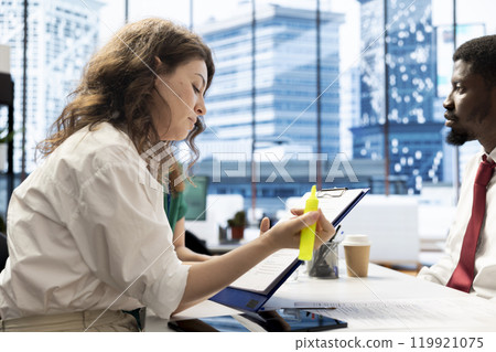 HR employee implementing diversity recruitment strategy for company, using highlighter marker on files. Recruiter doing interview with african american man, highlighting text on contract 119921075