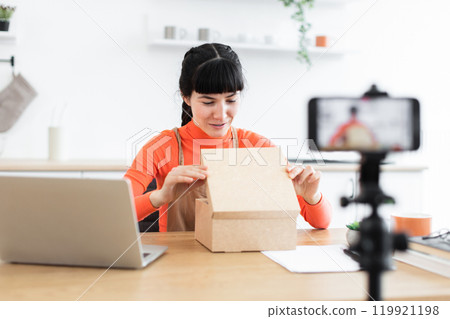 Caucasian female blogger unboxing goods during online video recording 119921198