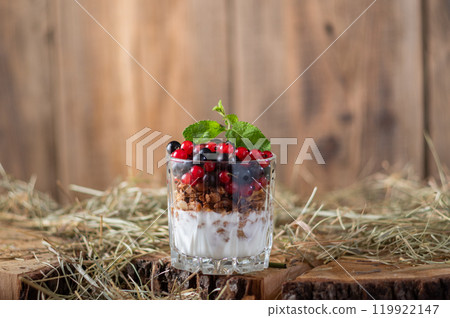 Glass with granola and fresh berries. Red and black currants in a glass. Country style. Glass with granola and fresh berries. Red and black currants in a glass. Country style. 119922147