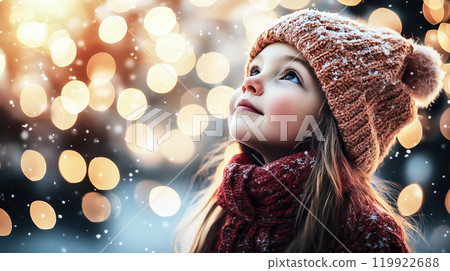Little girl wearing winter clothes looking up at christmas lights 119922688