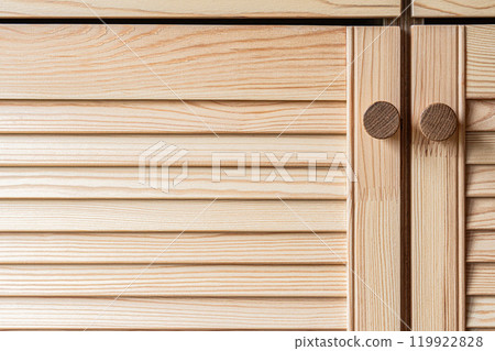 Wooden louvered doors with knob handles close-up view 119922828