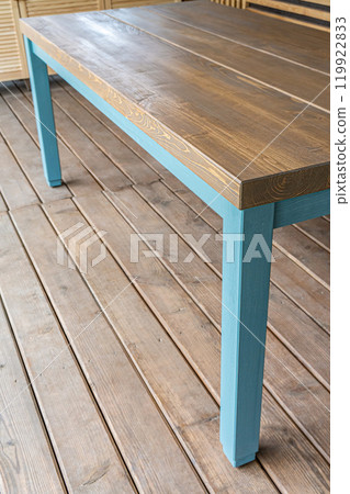 Dining table is made of pine wood with blue legs on terrace Dining table is made of pine wood with blue legs on terrace 119922833