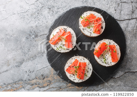 Mini cheesecake salmon with cream cheese, sesame and micro greens close-up on slate plate. Horizontal top view 119922850