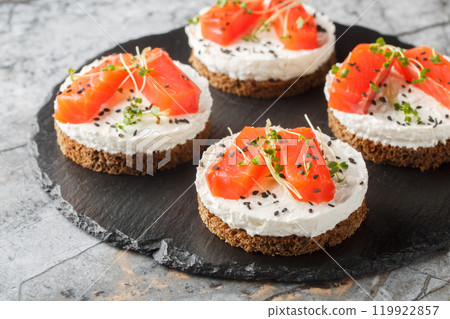 Mini cheesecake salmon with cream cheese, sesame and micro greens close-up on slate plate. Horizontal 119922857