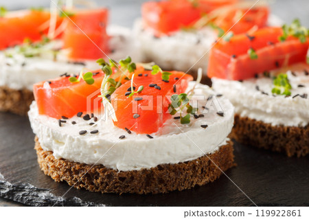 Healthy rye bread sandwich with red fish, cream cheese, sesame and microgreens close-up on slate plate. Horizontal Healthy rye bread sandwich with red fish, cream cheese, sesame and microgreens close-up on slate plate. Horizontal 119922861