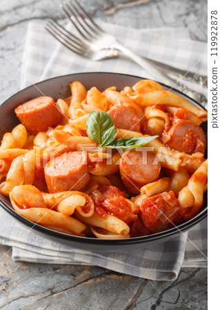 Italian Treccione pasta served with tomato, onion, sausage and basil close-up in a bowl. Vertical 119922878