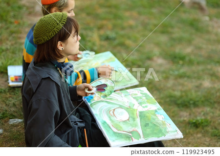 Creative Spirit. The Young Artist in Nature. a young female artist passionately painting outdoors, with brushes and paints in her hands. Surrounded by the beauty of nature, she is fully immersed in 119923495