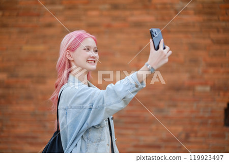 A girl with pink hair is taking a selfie with her cell phone 119923497