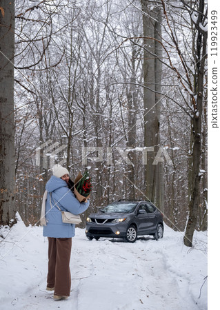 Person with Flowers in Snowy Forest SUV on background 119923499