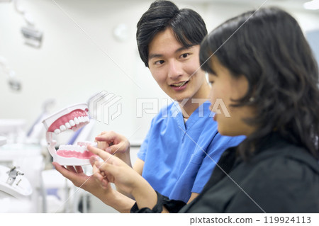 Dentist teaching patient how to brush teeth 119924113