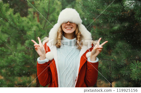 Winter portrait of happy smiling woman having fun enjoys snow against Christmas tree in forest 119925156
