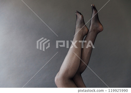 Beautiful female legs in black tights stockings on a gray background 119925990