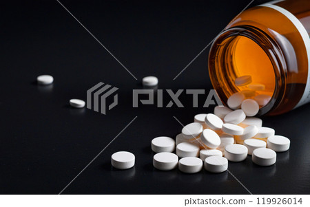 pills in orange bottle on black background pills in orange bottle on black background 119926014