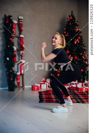 blonde woman doing fitness sport gymnastics at christmas tree for new year 119926320