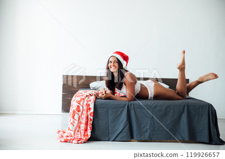 woman in lingerie on bed wearing Christmas Santa hat for new year 119926657