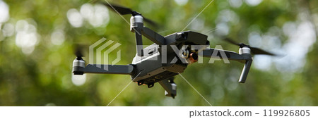 Header style background image of big high tech drone flying in air against greenery with camera recording video copy space Header style background image of big high tech drone flying in air against greenery with camera recording video copy space 119926805