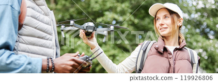 Header image of couple outdoors with young woman holding drone and enjoying nature videography in green forest copy space Header image of couple outdoors with young woman holding drone and enjoying nature videography in green forest copy space 119926806