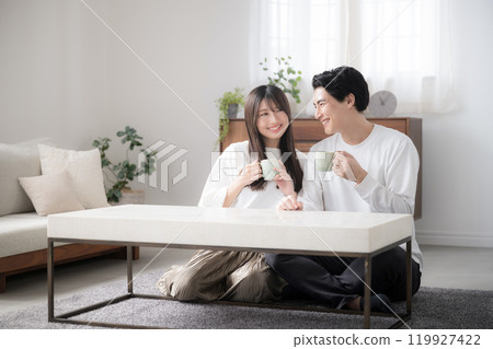 Couple relaxing in a room watching TV with drinks, wide angle Couple relaxing in a room watching TV with drinks, wide angle 119927422
