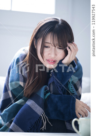 Close-up portrait of a woman in winter pajamas feeling so unwell with a cold that she has a severe headache Close-up portrait of a woman in winter pajamas feeling so unwell with a cold that she has a severe headache 119927543